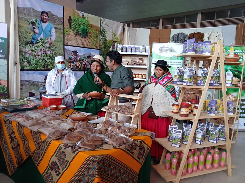 Emprendedoras junto a una exhibición de alimentos, textiles y productos locales en un encuentro de emprendimiento rural.